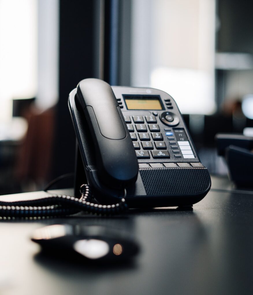 black ip desk phone on black wooden table